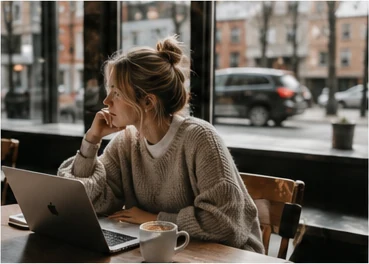 Creative freelancer working on a laptop beside a café window